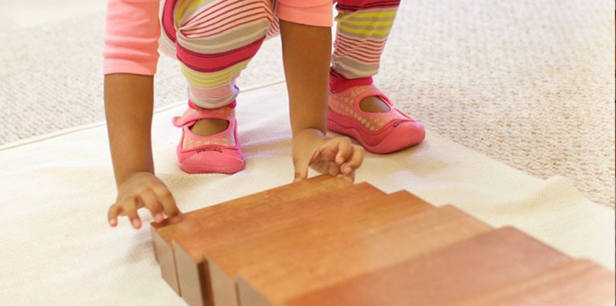 Niño manipulando los prismas de madera de la escalera marrón Montessori