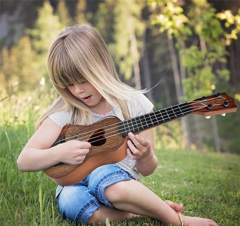 Niño tocando la guitarra acústica de madera Montessori con cuerdas de nailon